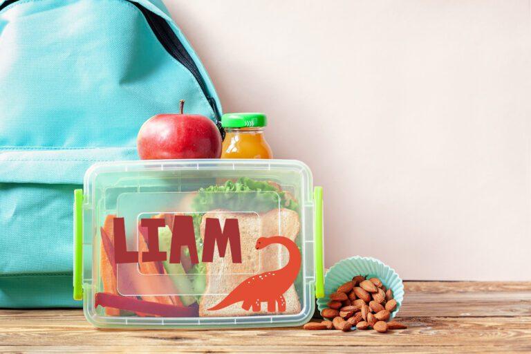 School lunch box with sandwich, vegetables, juice and almonds on table. Healthy eating habits concept.