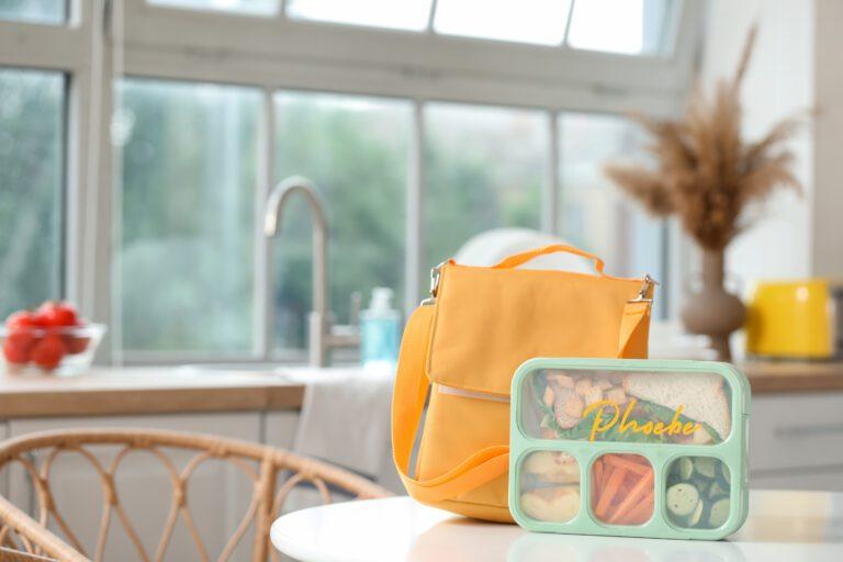 Backpack with school lunchbox on table in kitchen